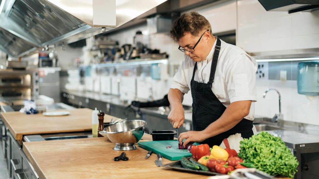 male chef with apron chopping vegetables