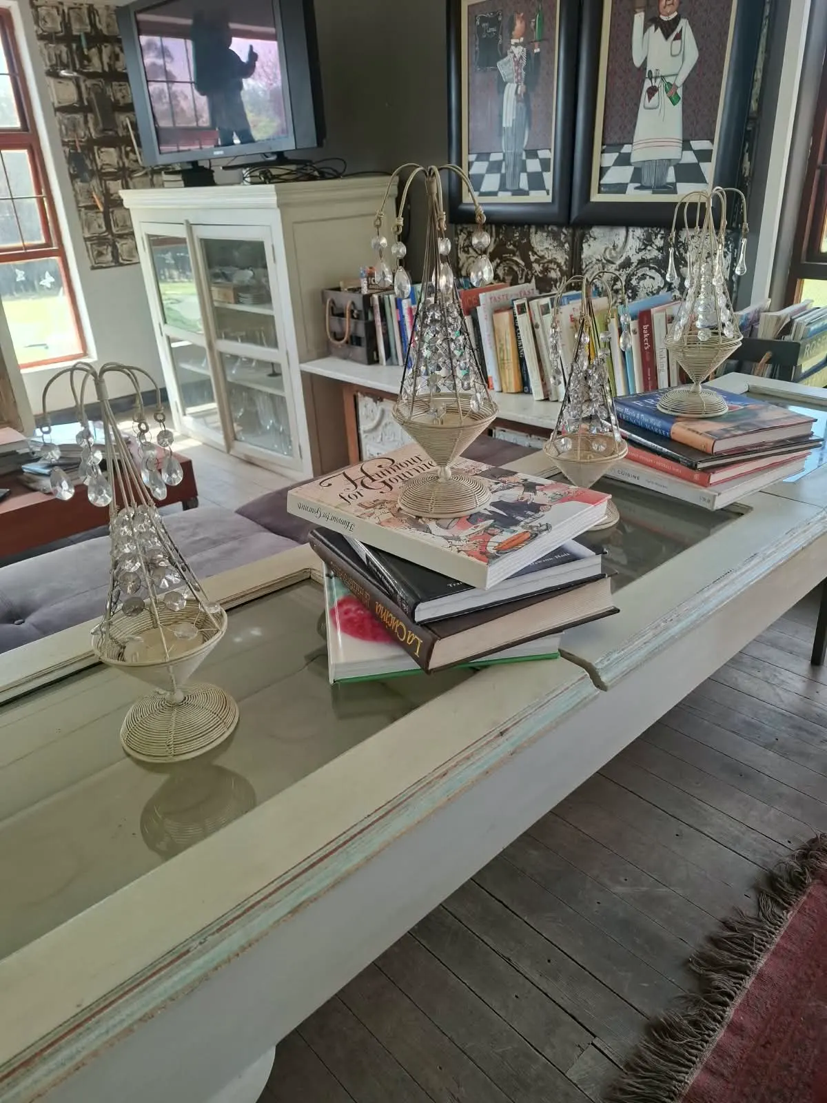 Stacked cookbooks and crystal candle holders on a glass-topped table