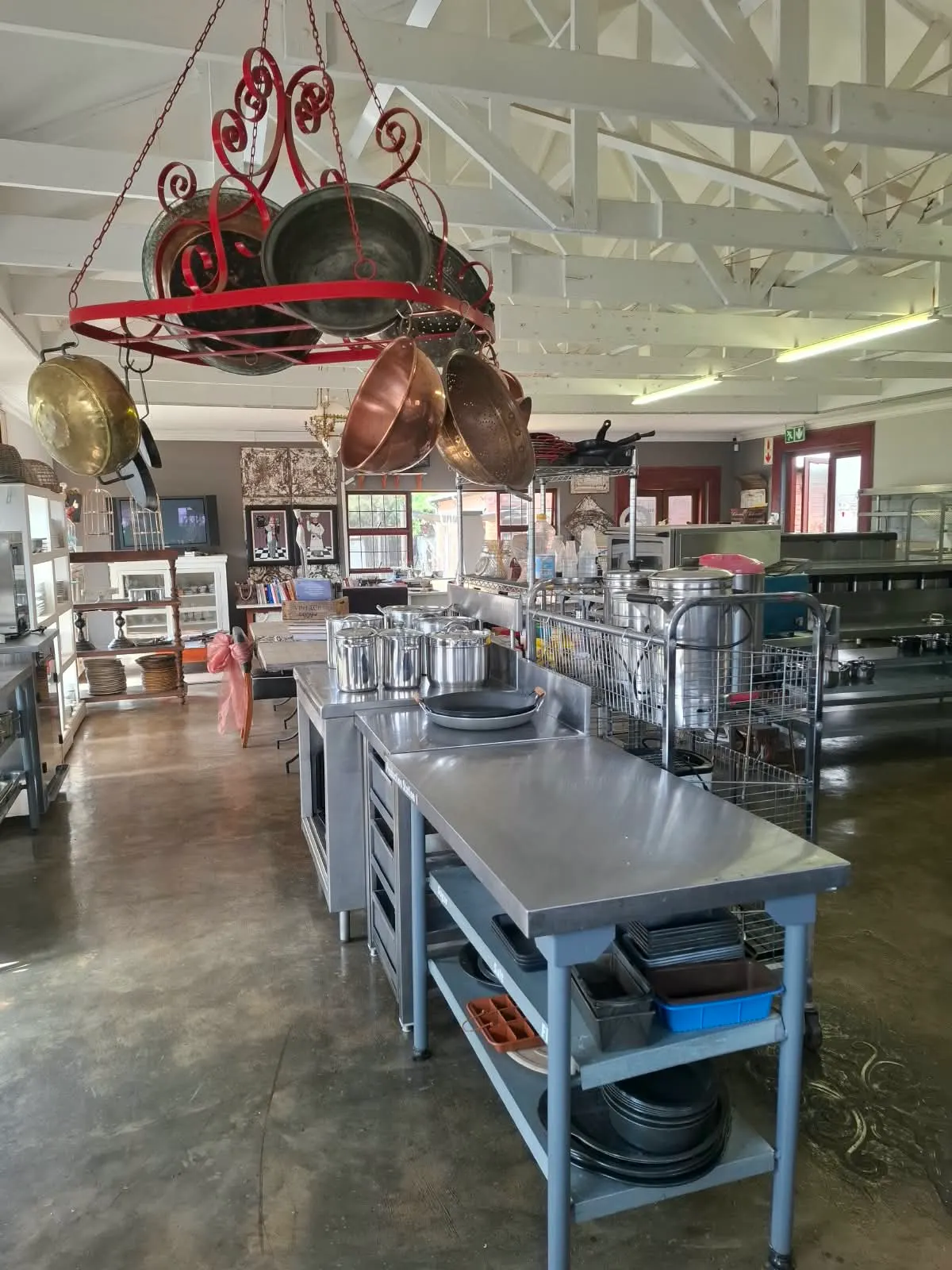 Copper and brass pans hanging from an iron rack above the training kitchen