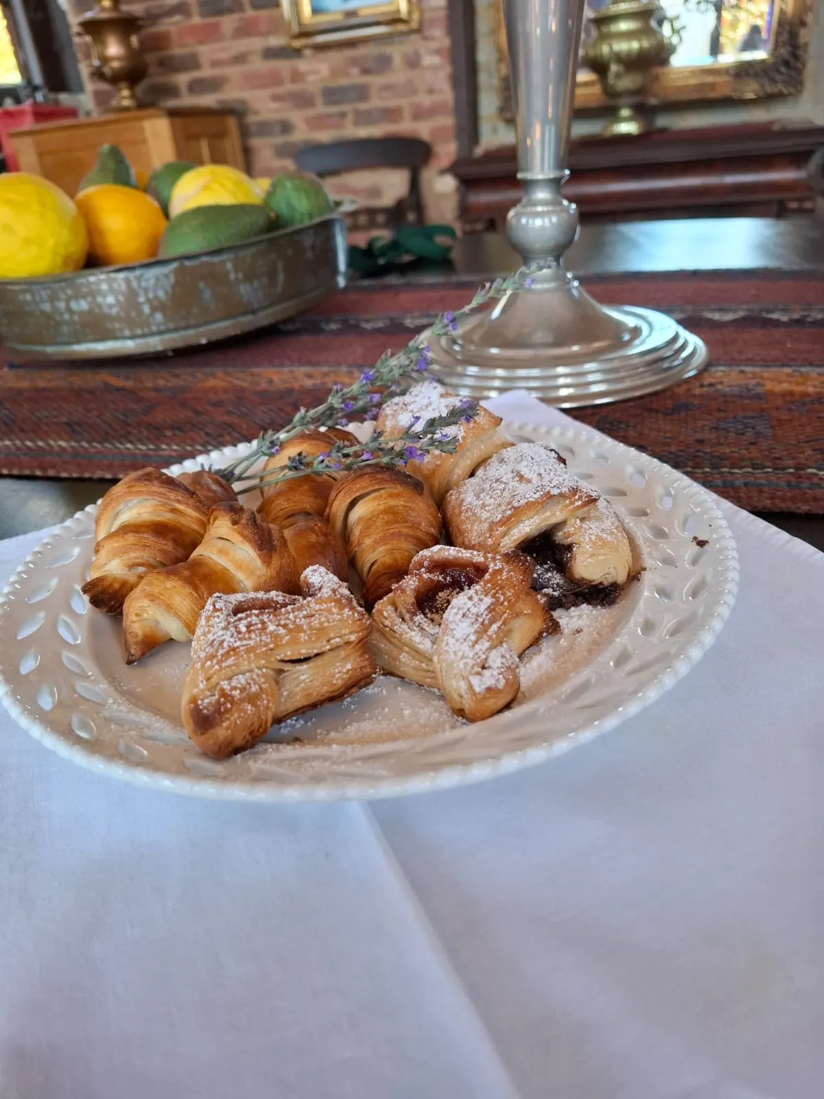 A plate of croissants and Danish pastries with lavender sprigs, lemons blurred behind.
