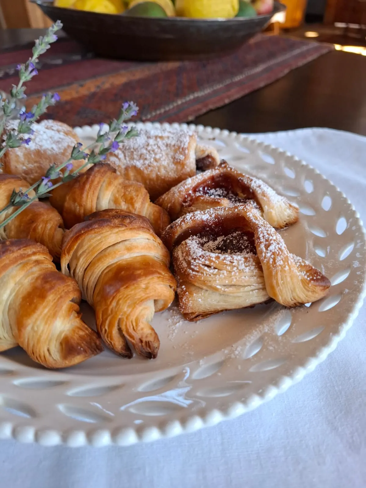 Close-up of flaky croissants and a jam-filled Danish pastry dusted with icing sugar.