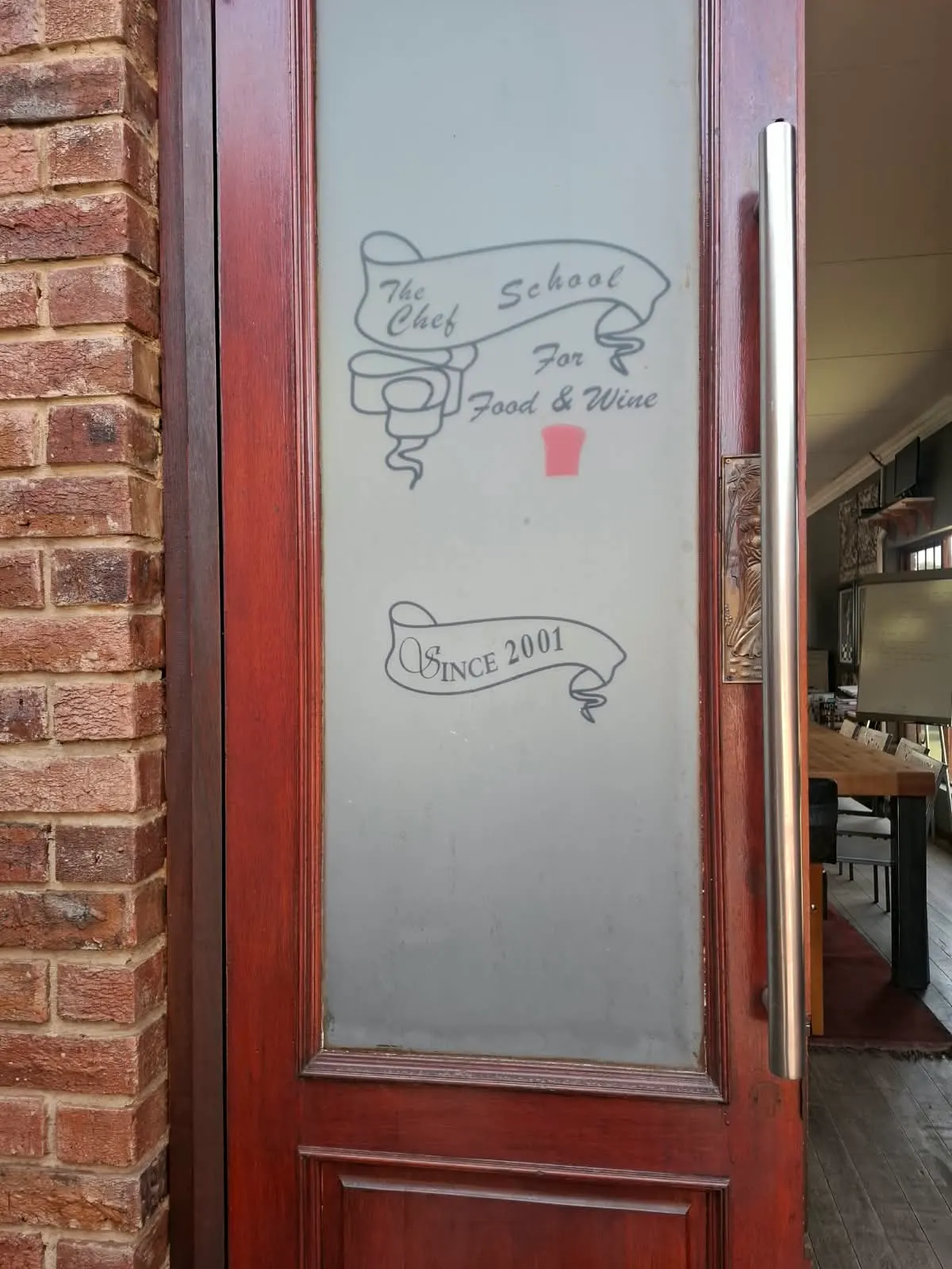 Wooden entrance door etched with The Chef School logo and the words Since 2001