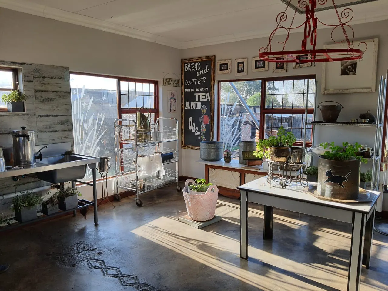 Sunlit prep room with potted herbs, copper pots and a chalkboard sign