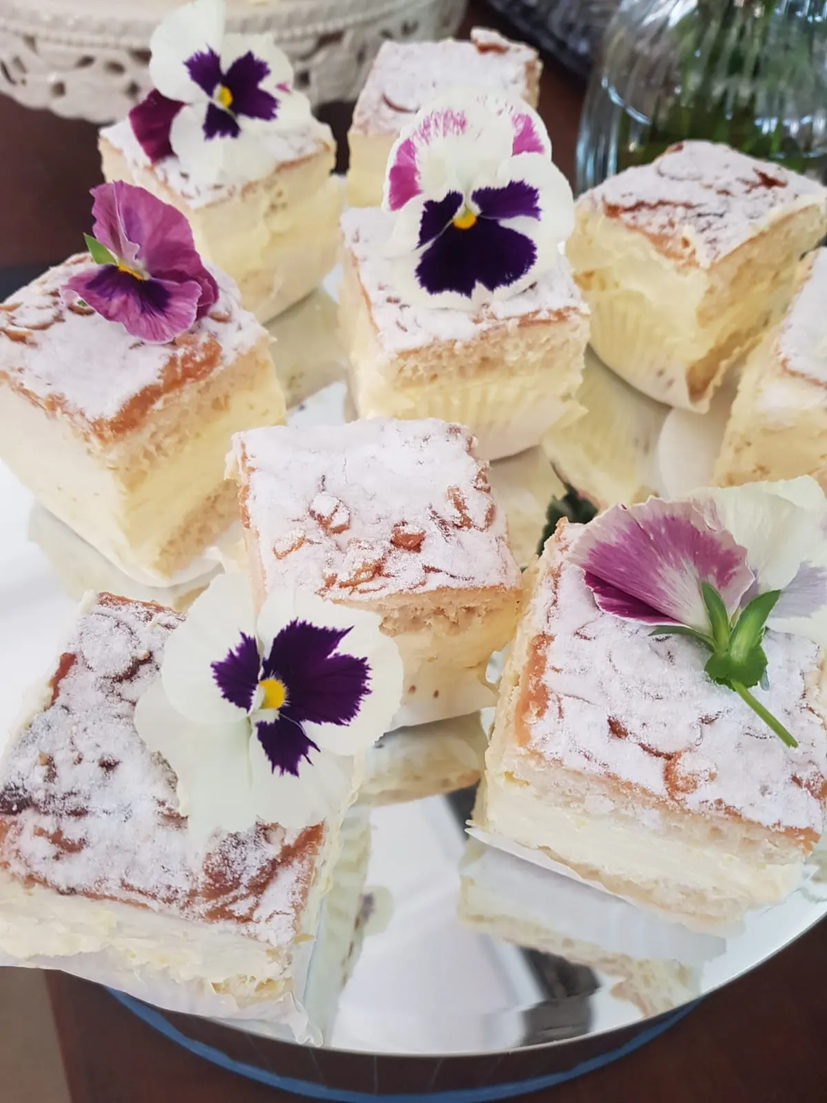 Custard slices dusted with icing sugar and topped with edible pansies