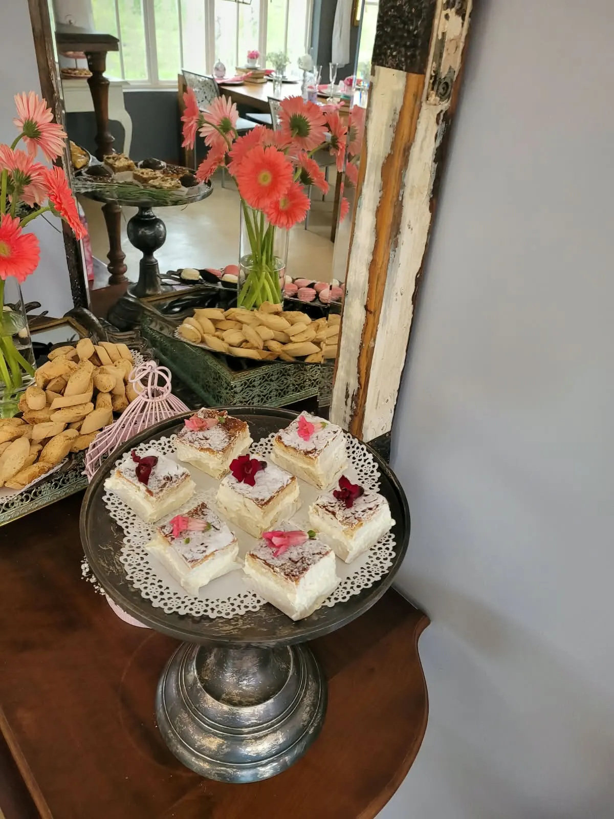 Custard slices with rose petals on a vintage cake stand in front of a mirror