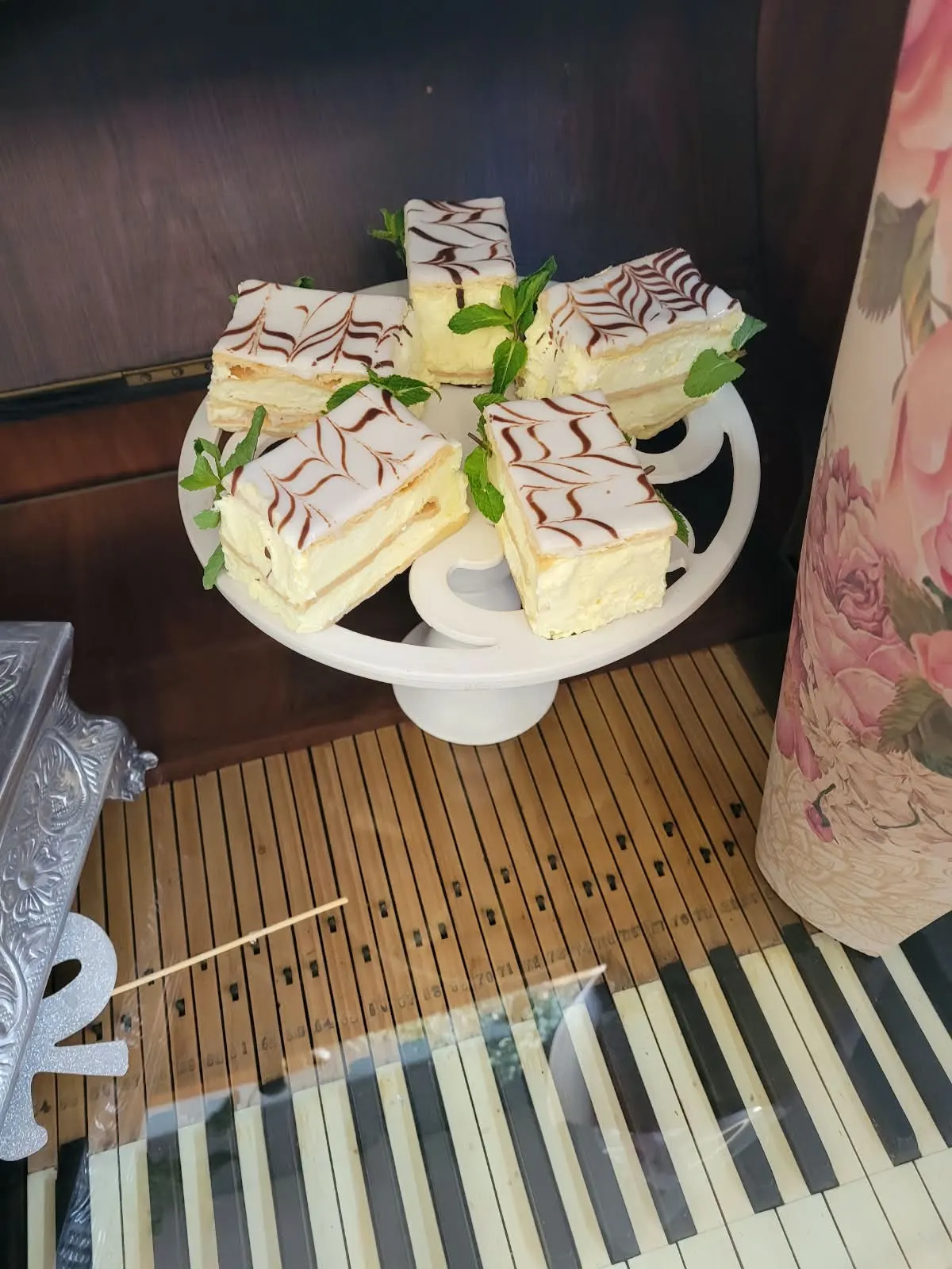 Mille-feuille slices with feathered icing and fresh mint on a cake stand