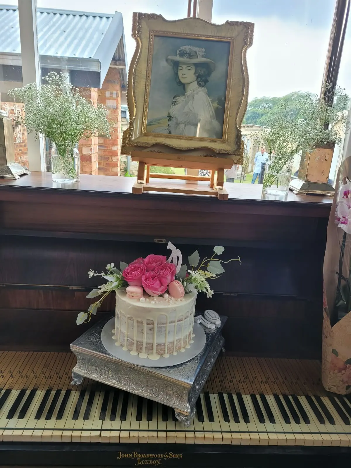 Celebration cake with pink roses on an antique piano beneath a framed portrait