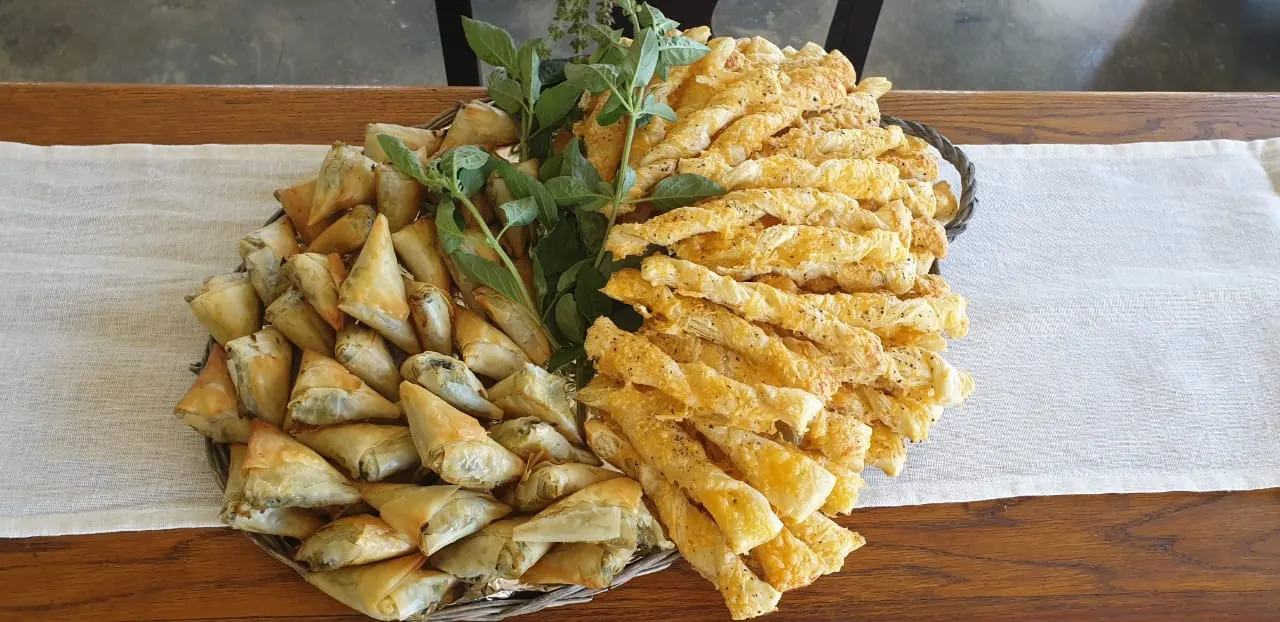 Platter of spinach phyllo triangles and cheese straws with fresh basil